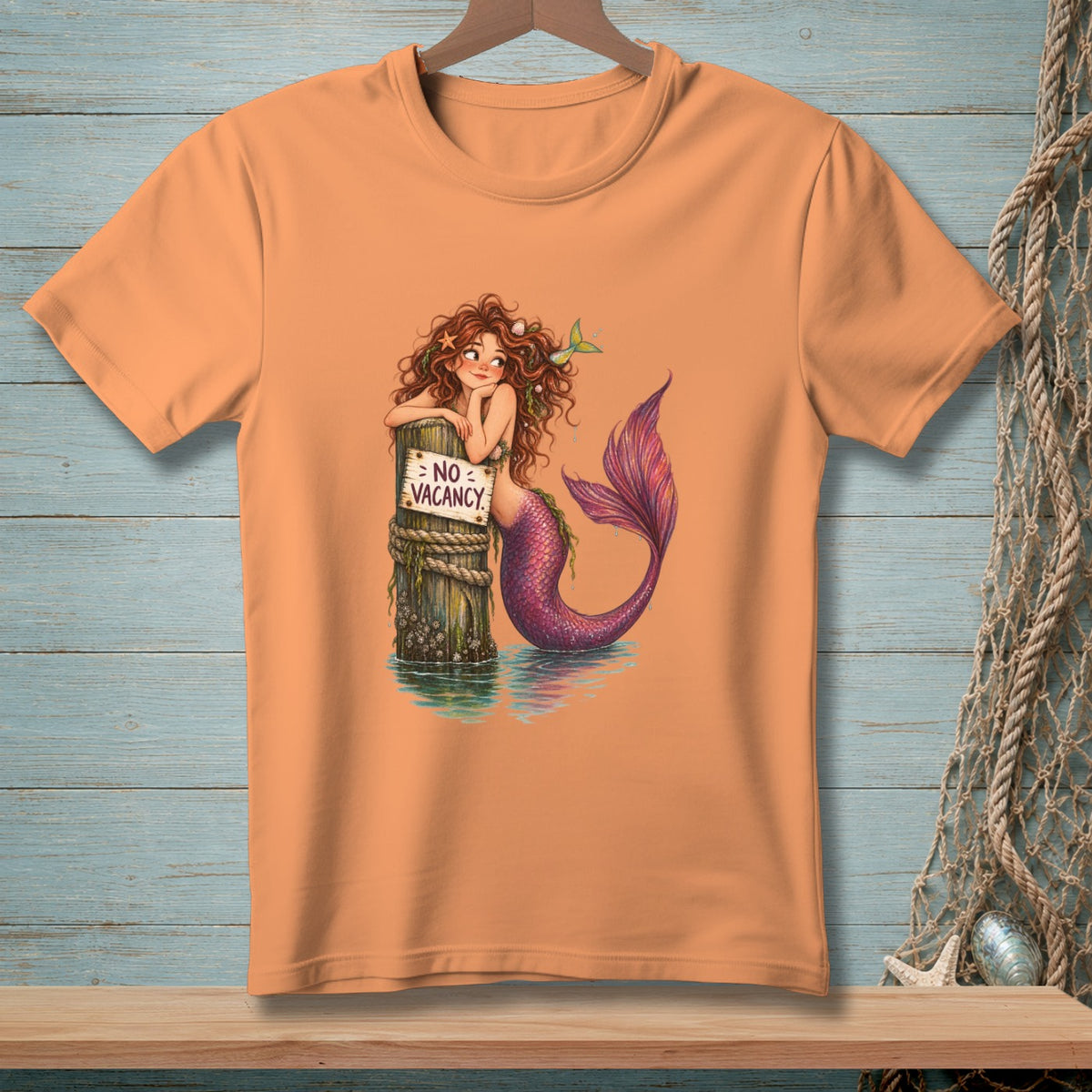 Orange t-shirt with a mermaid leaning on a post reading "No Vacancy".