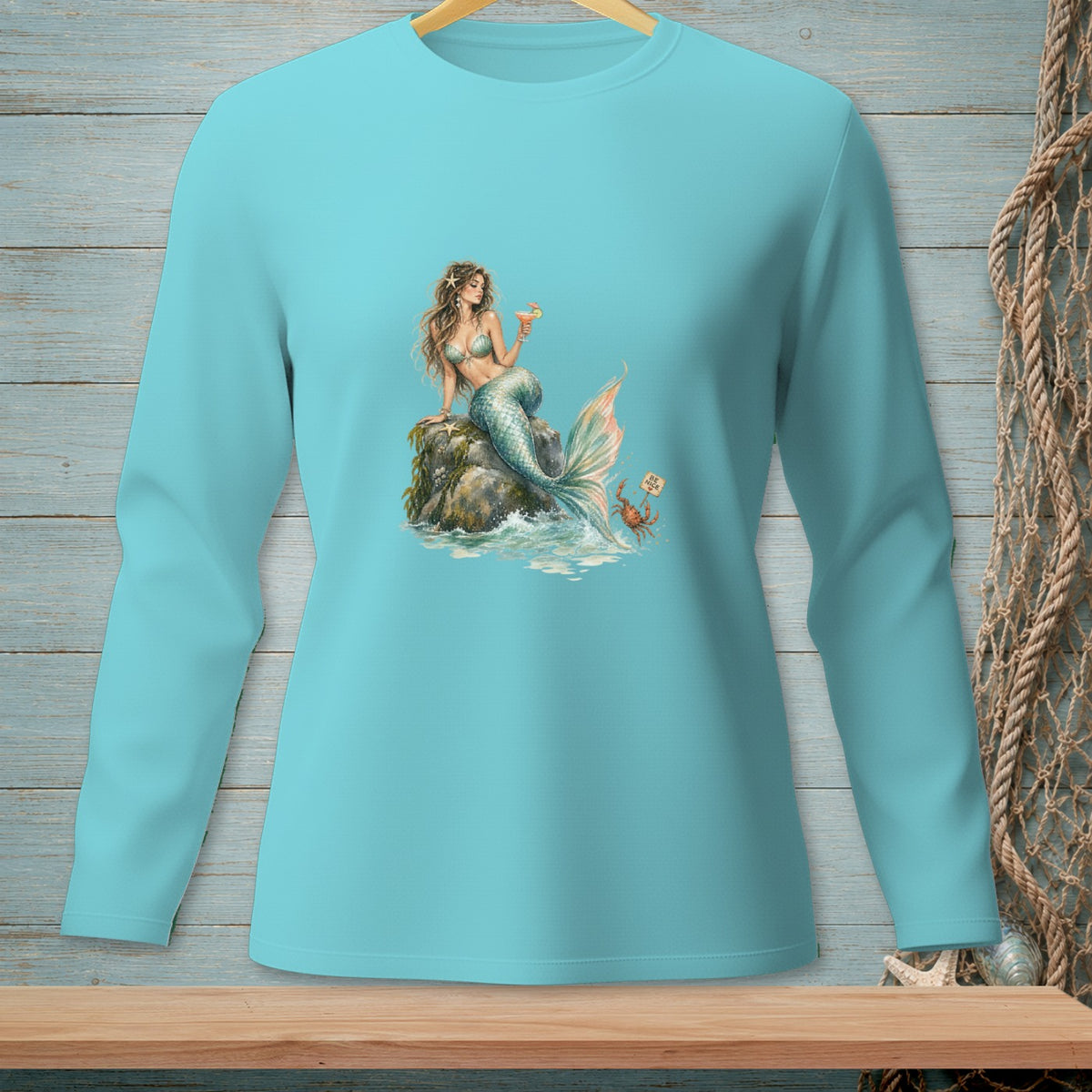 Mermaid on a rock holding a drink with a crab and sign on aqua shirt.