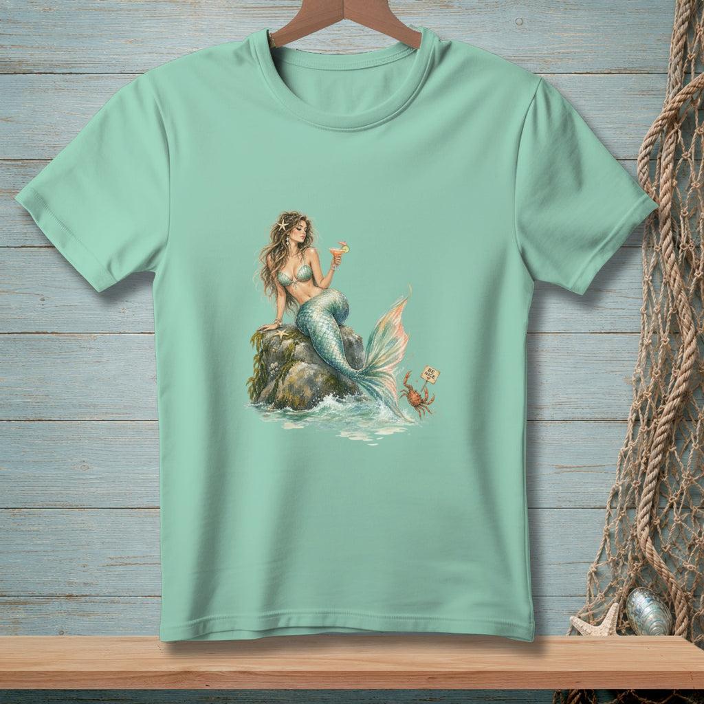 Mint t-shirt with a mermaid sitting on a rock holding a drink, a crab holds a "Be Nice" sign.