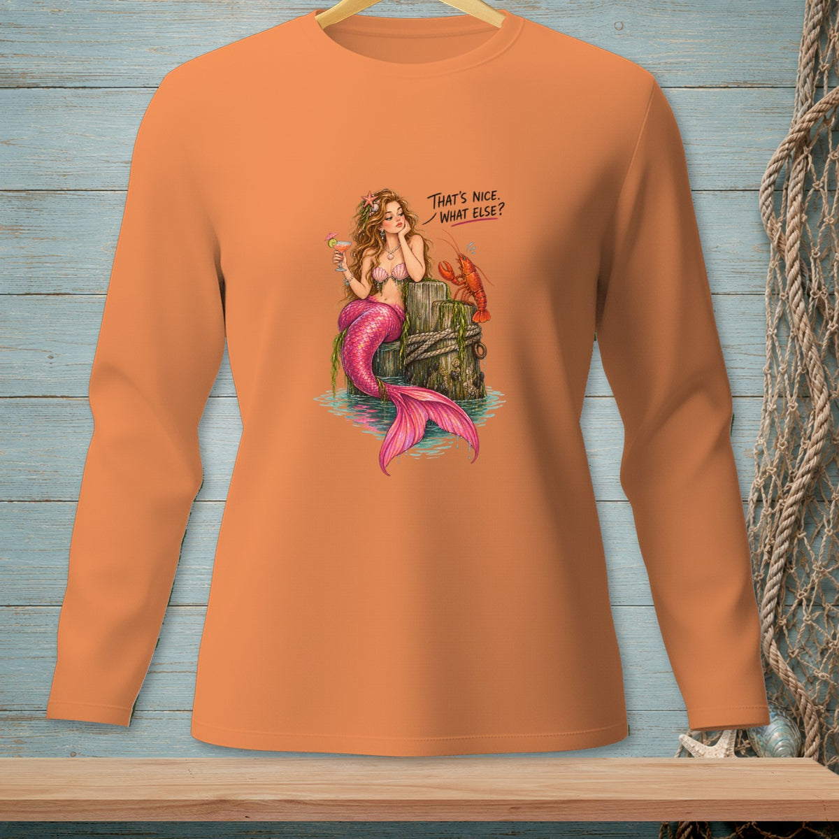 Orange long-sleeve shirt with a mermaid, lobster, and text: "THAT'S NICE. WHAT ELSE?".