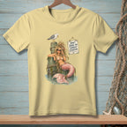Light yellow t-shirt graphic of a mermaid on a pilothwith a seagull and sign reading "Don't judge my current situation."