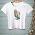White t-shirt with mermaid on dock with crab and sailboats in background.