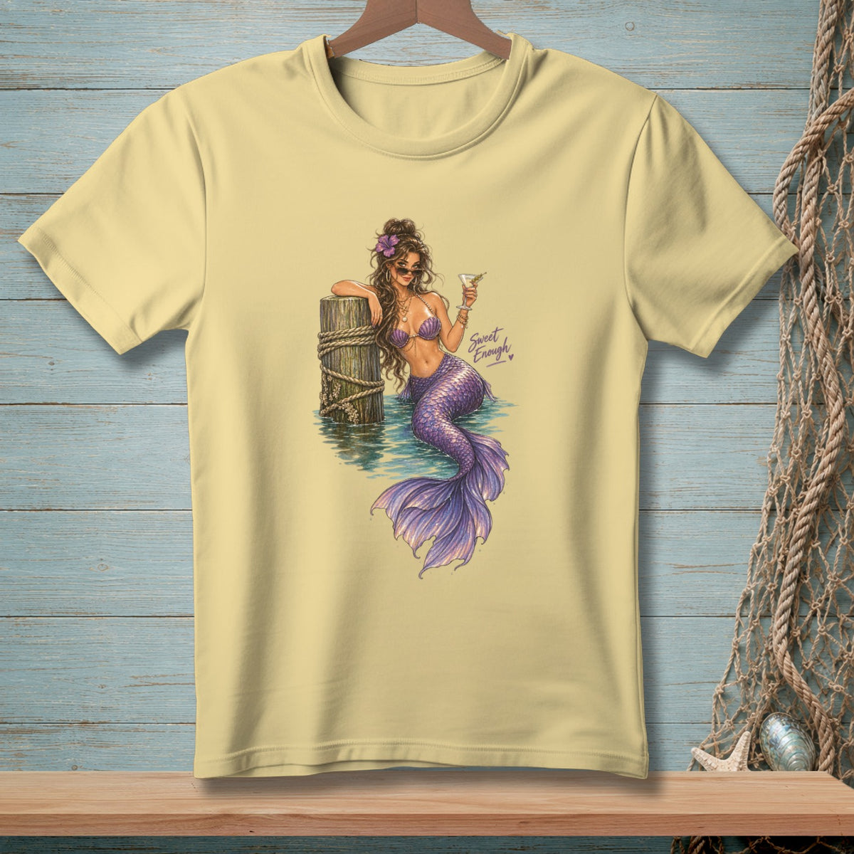 Pale yellow t-shirt with a mermaid illustration holding a martini and text "Sweet Enough".