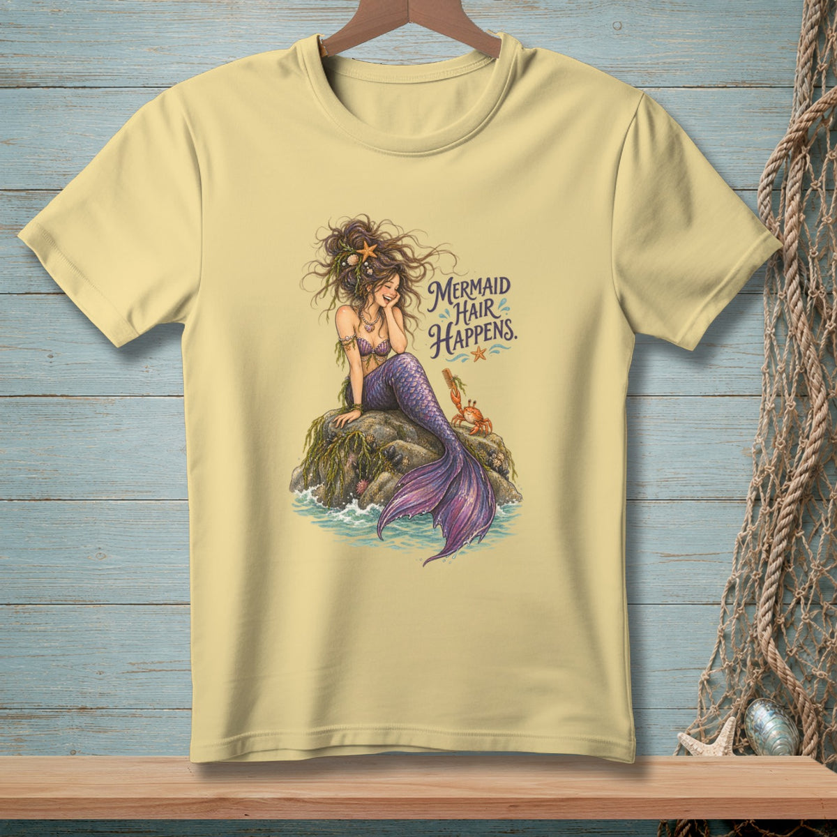 Light yellow t-shirt with a mermaid and crab graphic and text "Mermaid Hair Happens."