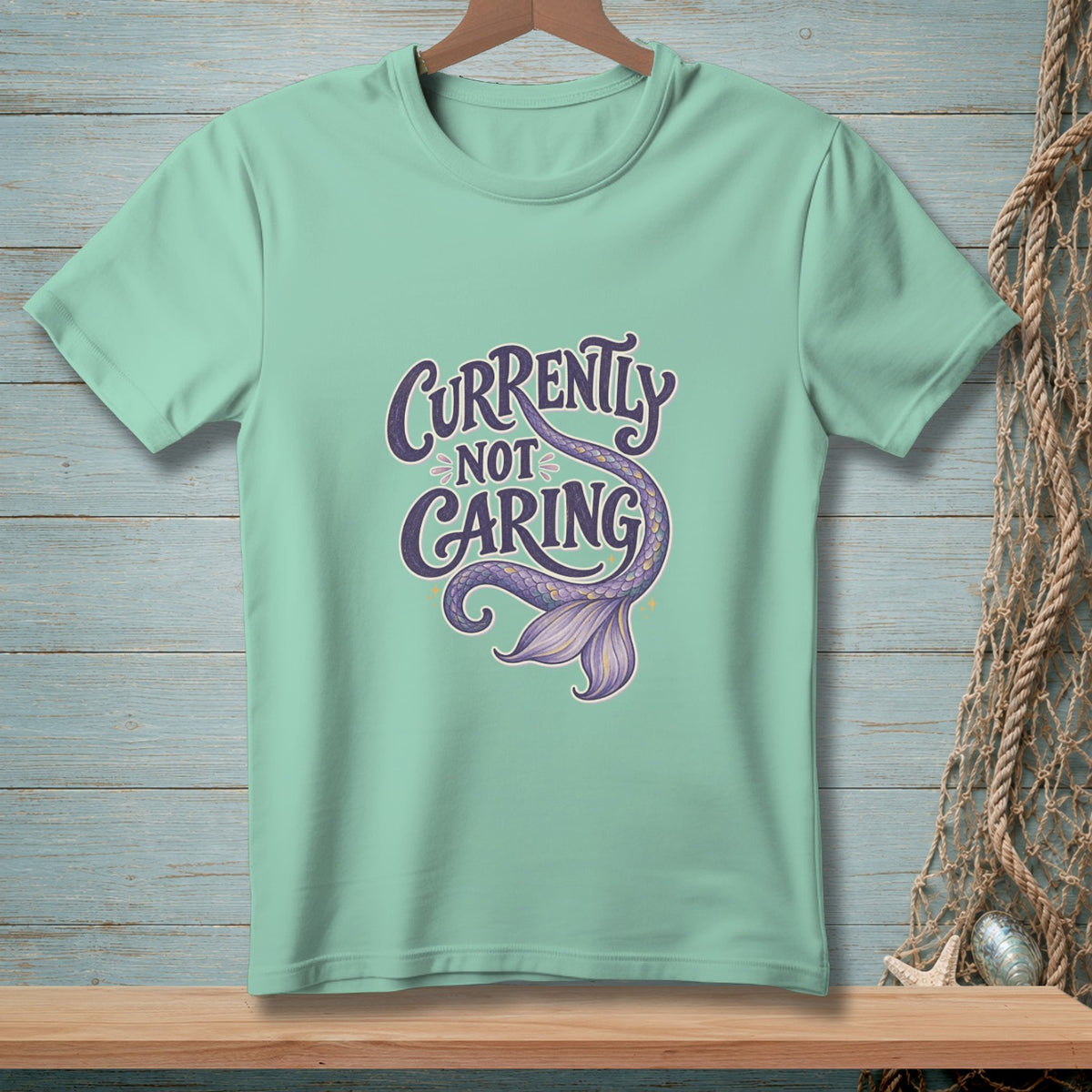 Mint t-shirt with purple text "Currently Not Caring" and a mermaid tail.