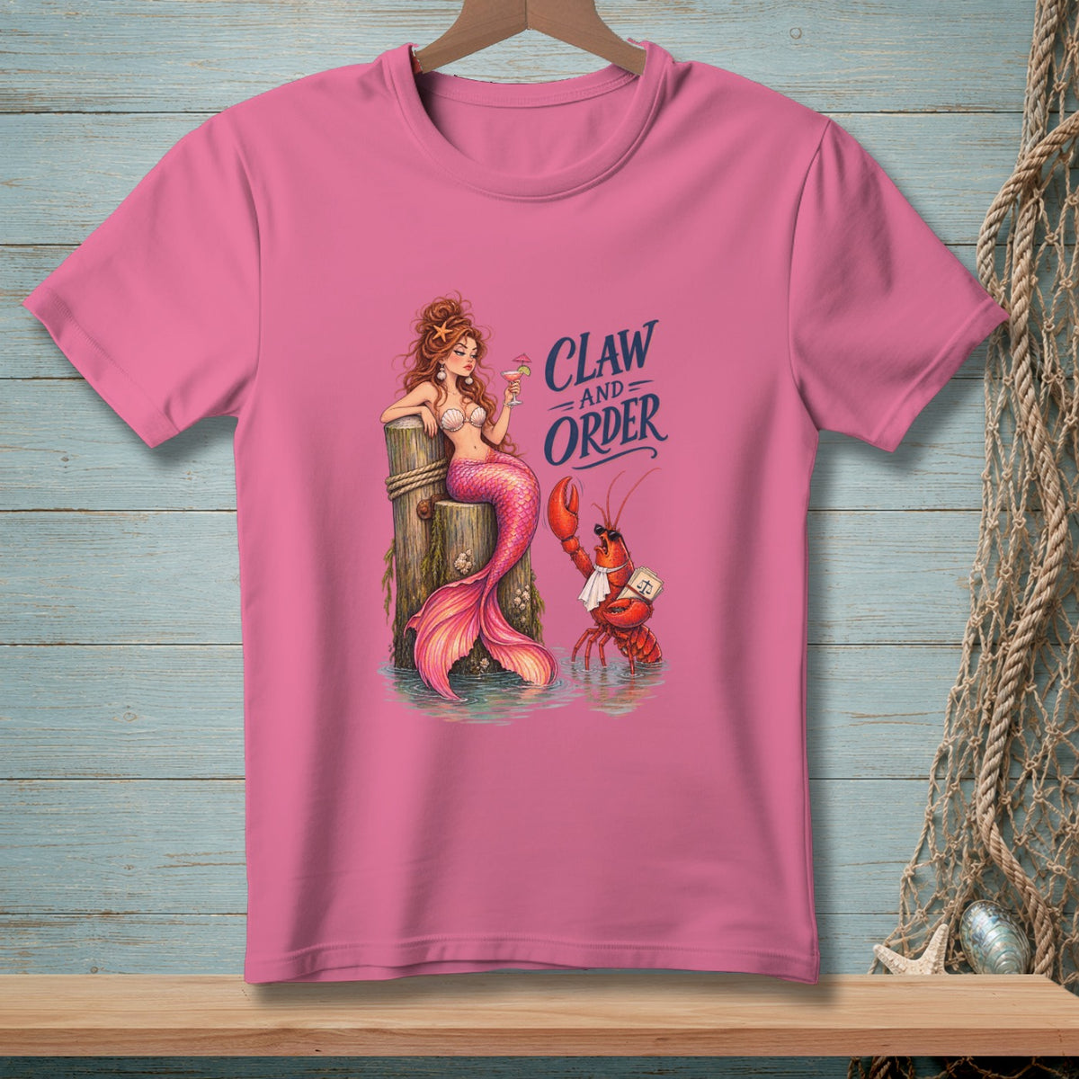 Pink t-shirt with mermaid and lobster graphic reading "CLAW AND ORDER".