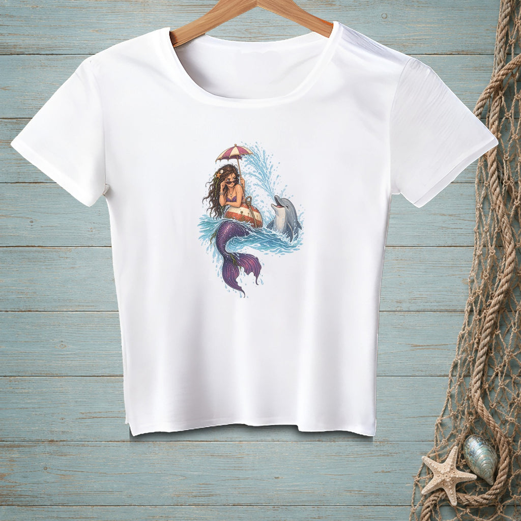 White t-shirt with graphic of a mermaid under an umbrella with a dolphin.
