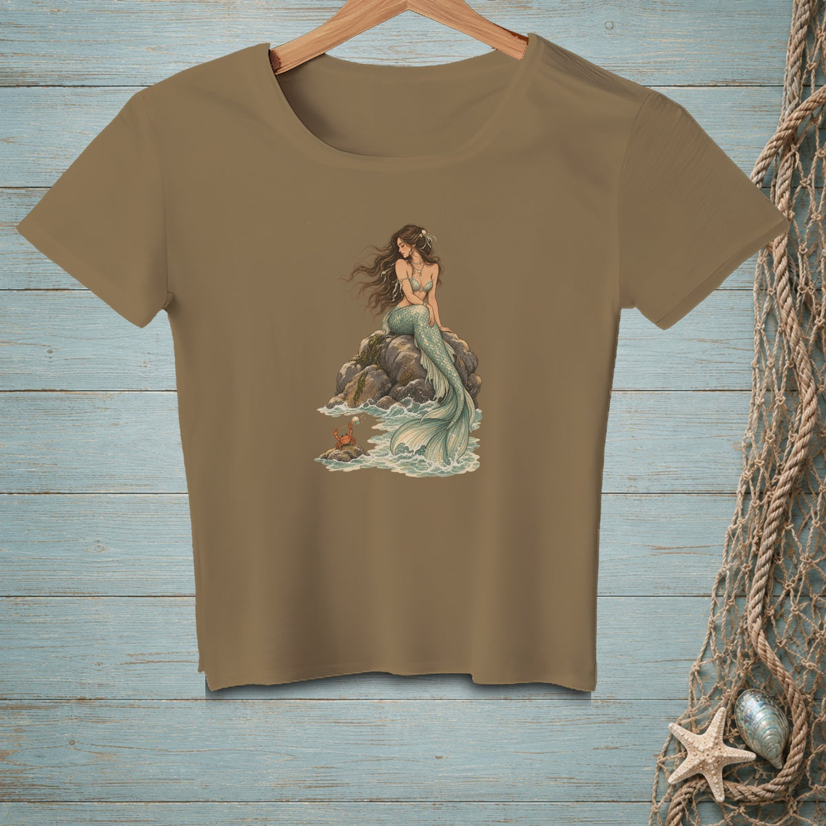 Mermaid sitting on rocks with a crab at her feet, on a taupe t-shirt.
