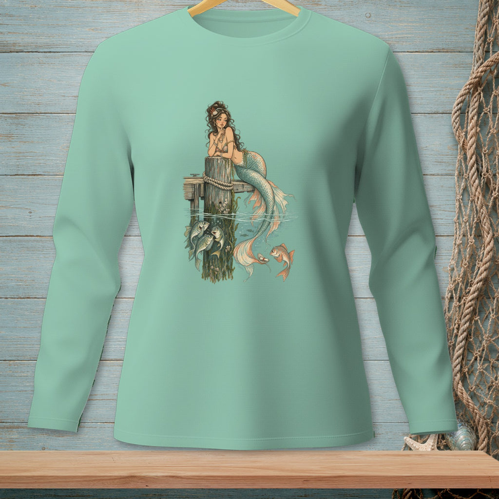 Mermaid lounging on a pier post, with fish swimming below and a goldfish nearby.