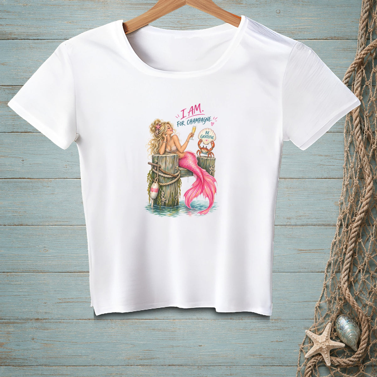 White t-shirt with mermaid graphic: "I AM. FOR CHAMPAGNE. BE GRATEFUL."