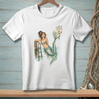 White t-shirt with watercolor graphic of a mermaid on a dock, and a sign.