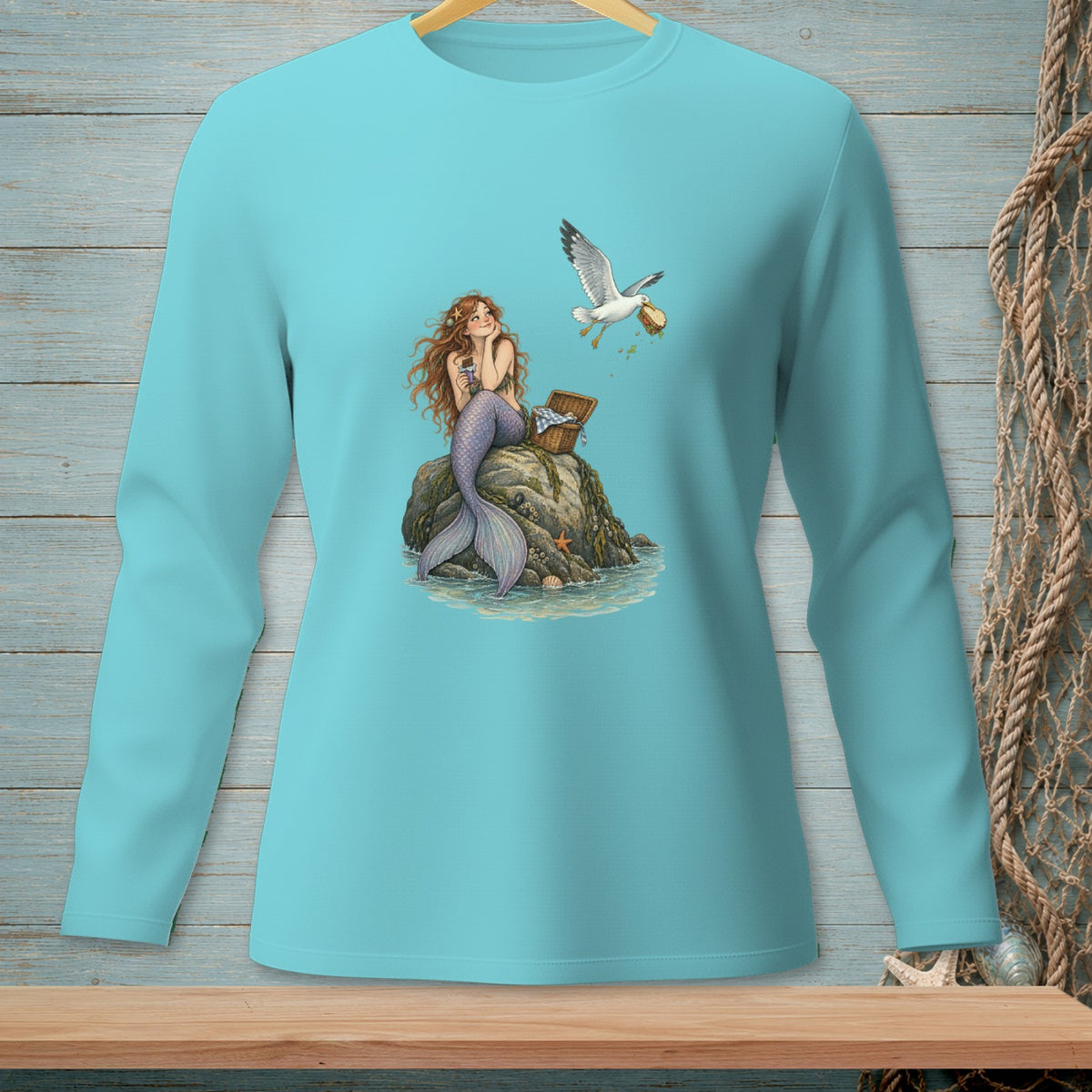 Mermaid with long hair sits on a rock as a seagull steals food from a picnic basket.