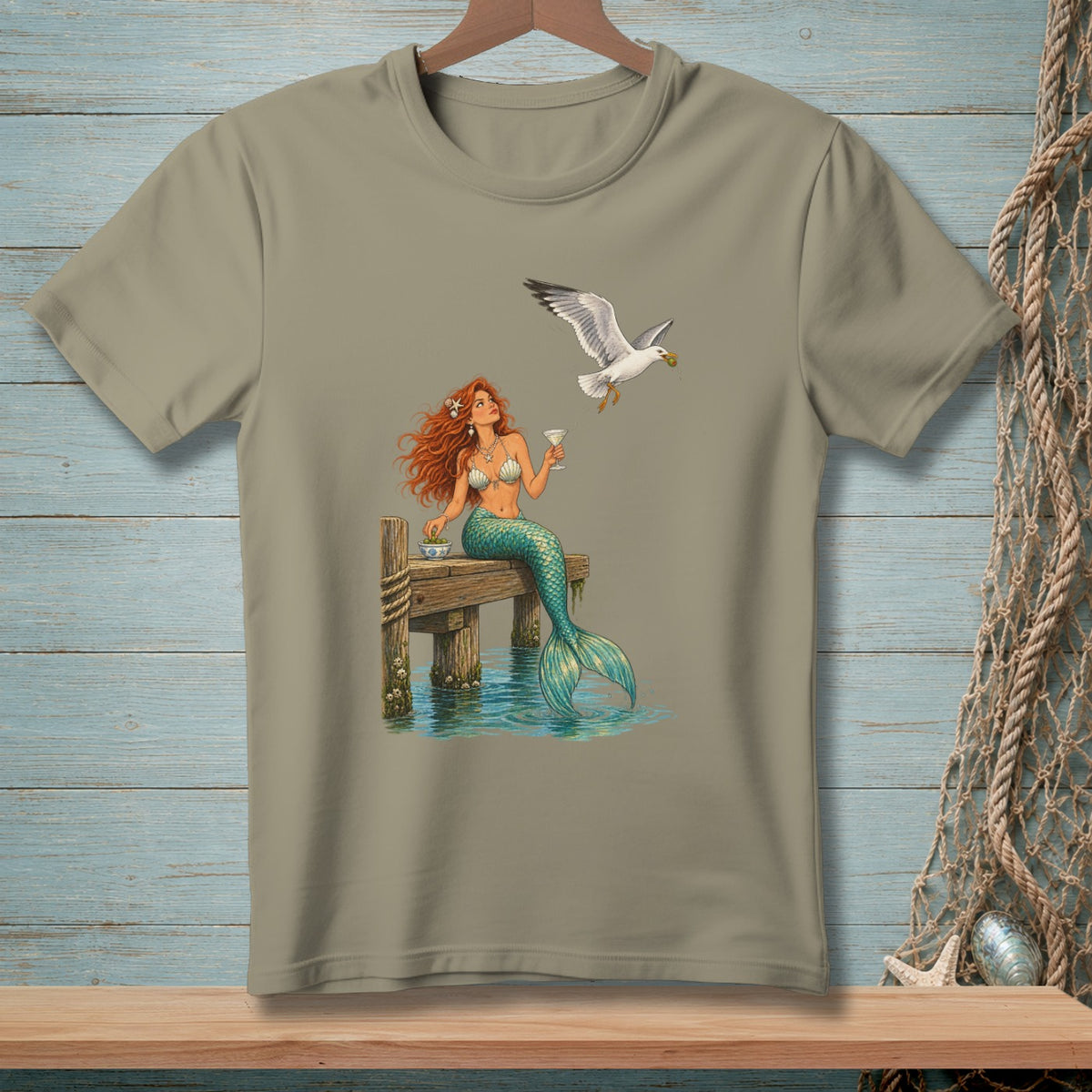 Mermaid with red hair sitting on a dock with a seagull flying overhead.