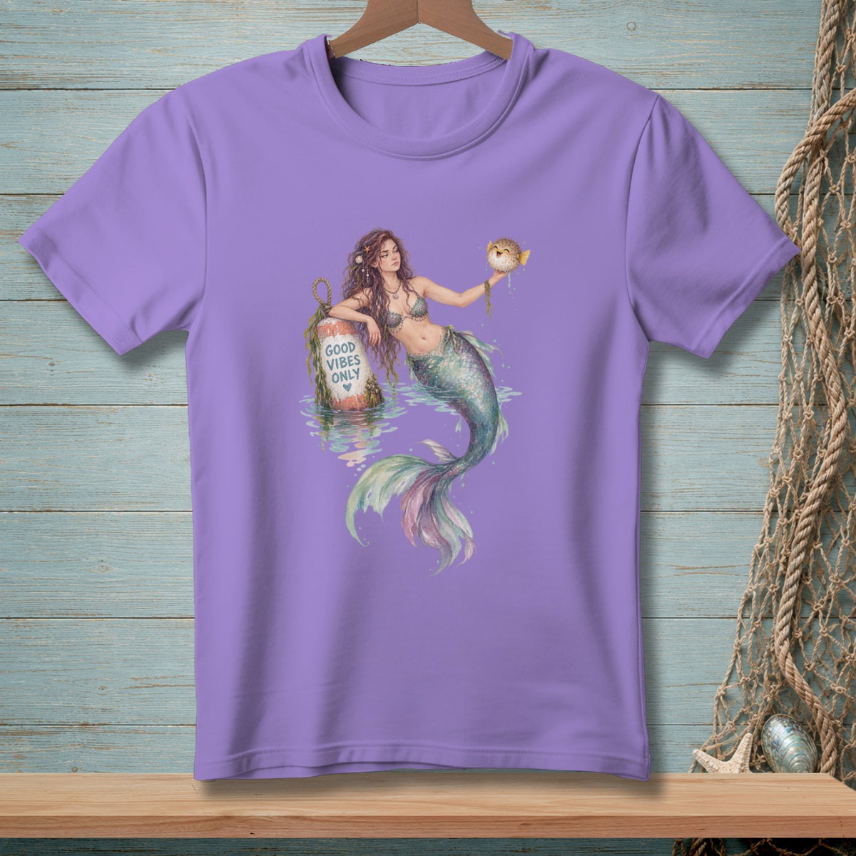 Lavender t-shirt with a mermaid holding a pufferfish, near a buoy reading "Good Vibes Only."
