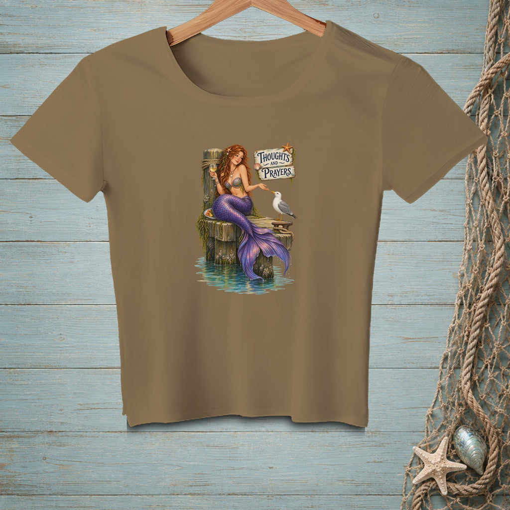 Brown t-shirt with mermaid on dock beside seagull and "Thoughts and Prayers" sign.