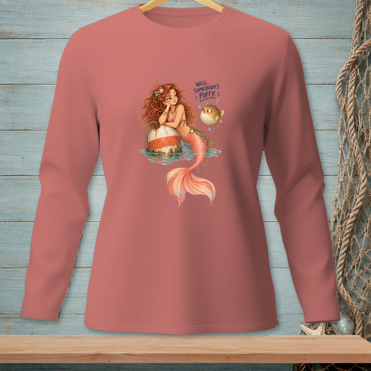 Mermaid with pufferfish on coral pink long-sleeve shirt, text "Well, somebody's puffy."