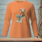 Orange long-sleeve shirt with a graphic of a mermaid relaxing on a dock with "ATTITUDE" sign.