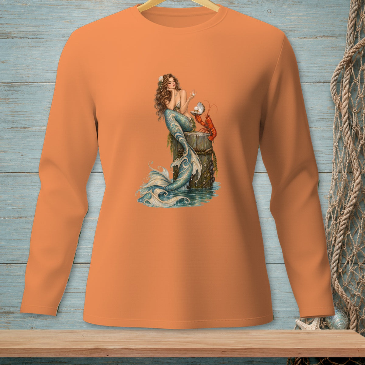Long sleeve orange shirt with a graphic of a mermaid and lobster by the water.