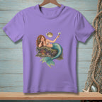 Mermaid with a pufferfish and martini on a rock, printed on a lavender t-shirt.