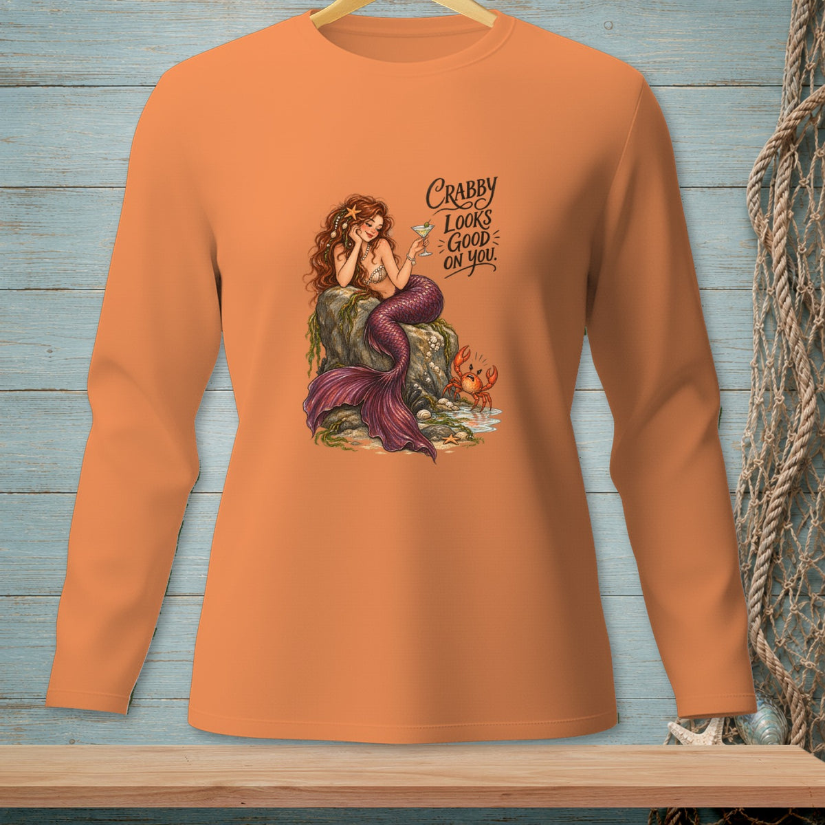 Orange long-sleeved shirt with mermaid, crab, and text "Crabby Looks Good On You".