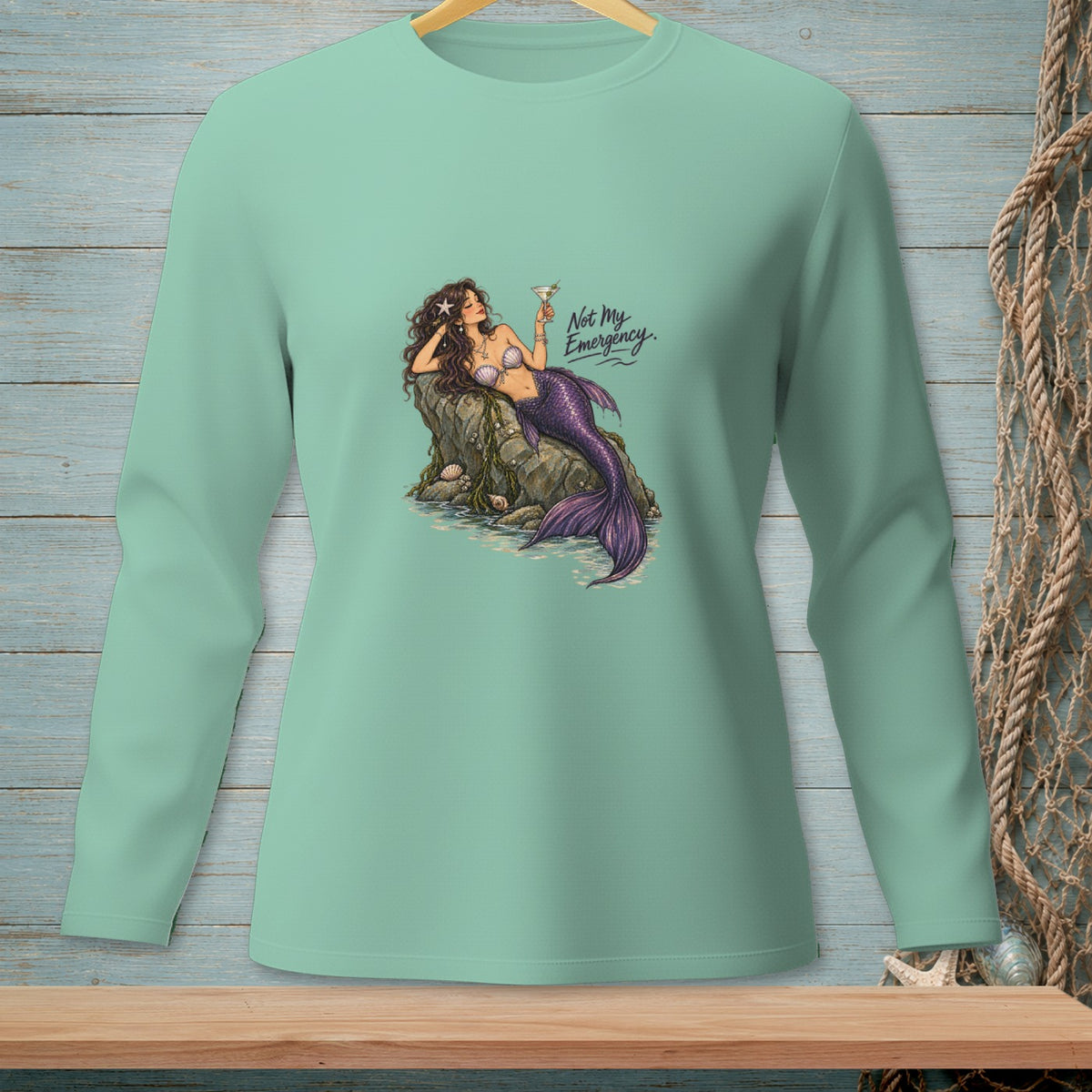 Mint green long-sleeve shirt with mermaid graphic and "Not My Emergency" text.