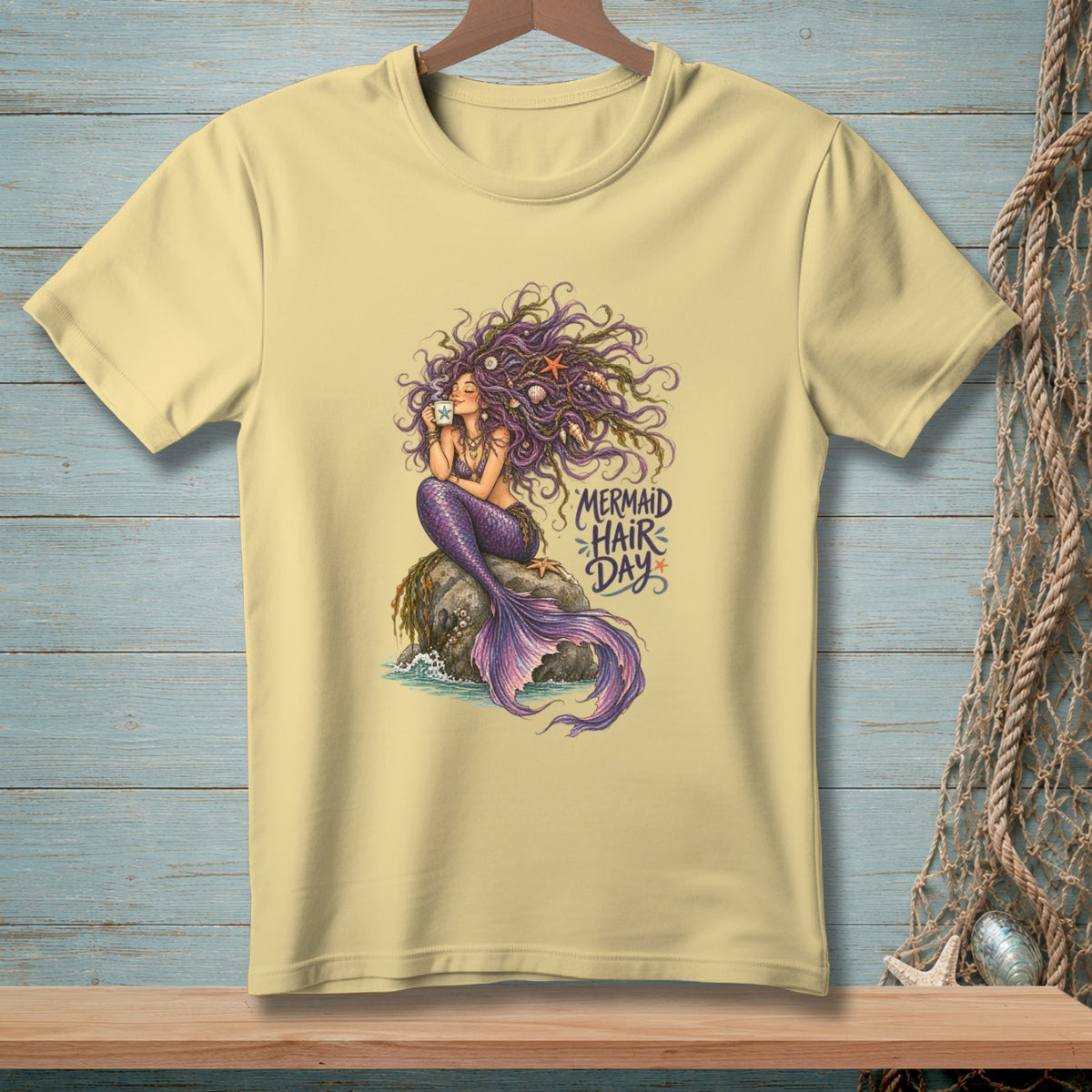 Light yellow t-shirt with a mermaid illustration holding a mug and text "Mermaid Hair Day".