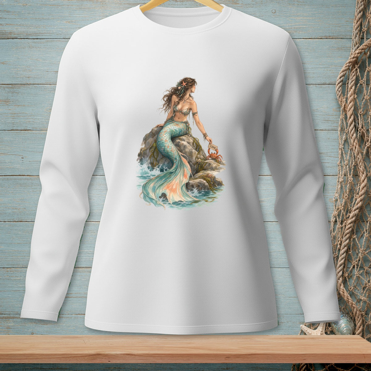 White long sleeve shirt with a mermaid sitting on a rock holding a crab.