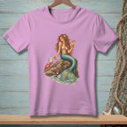 Pink t-shirt with a print of a mermaid holding a drink, sitting on a rock with a crab.