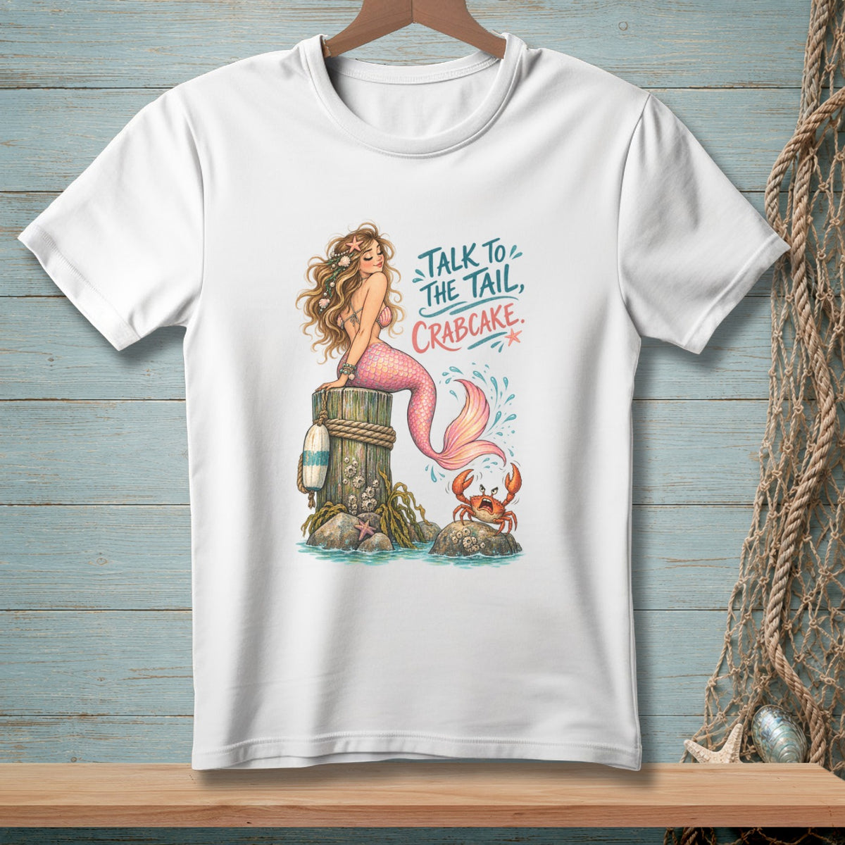 White t-shirt with mermaid and crab graphic that says "Talk to the tail, Crabcake."