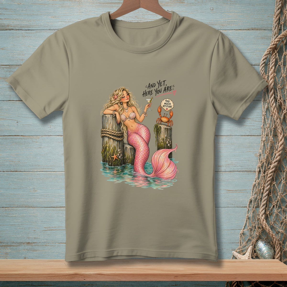 T-shirt graphic with a mermaid, crab, and text "AND YET, HERE YOU ARE" and "TOO MUCH ATTITUDE".