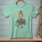 Mint green t-shirt featuring a mermaid holding a conch shell on a rock.