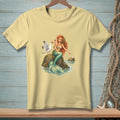 Pale yellow t-shirt with a mermaid and seagull on a rock illustration.