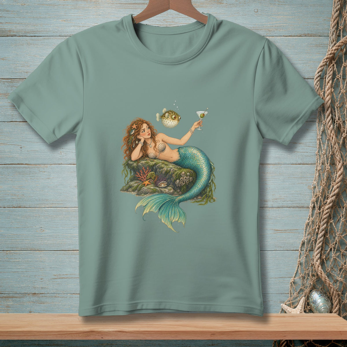 Mermaid on rock holding martini with pufferfish nearby on t-shirt.