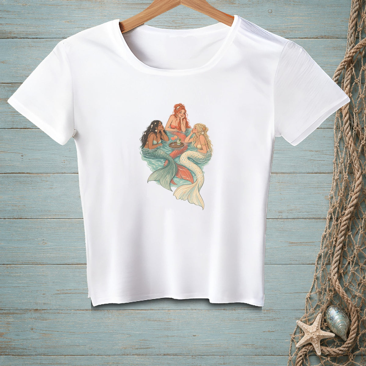 White t-shirt with a graphic of three mermaids socializing in water with drinks.