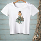 White t-shirt with a mermaid sitting on a rock, holding a seashell.