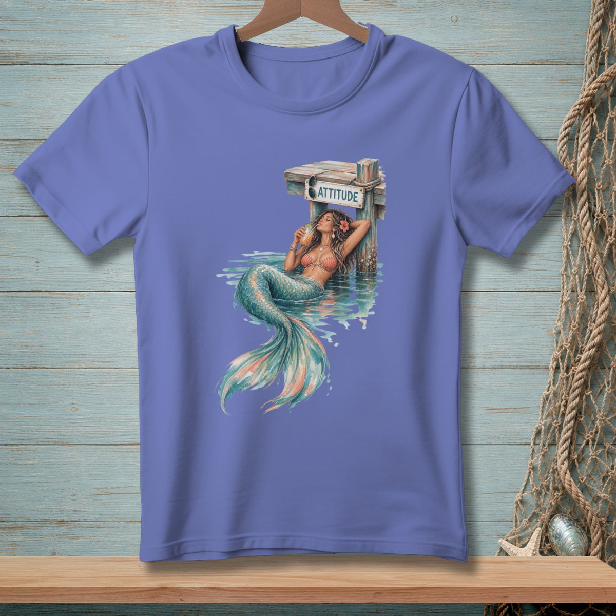 T-shirt with mermaid artwork leaning against a dock post with the word ATTITUDE.