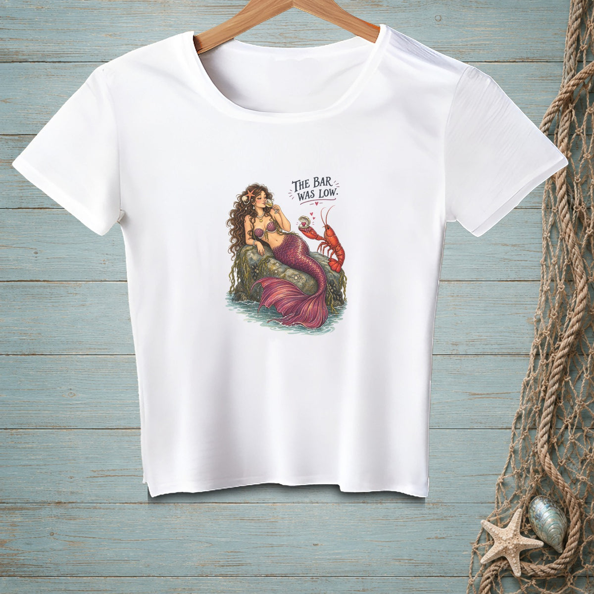 White t-shirt with mermaid and lobster graphic and text "The bar was low."
