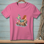 Pink t-shirt with a graphic of a mermaid on a rock with a seagull.