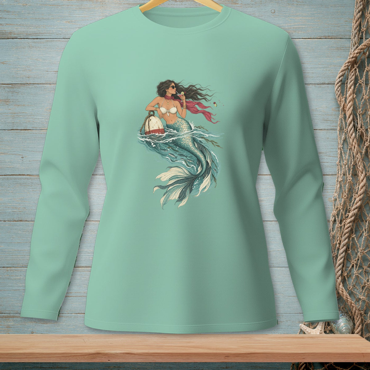 Mermaid holding a drink and leaning on a buoy in the ocean.