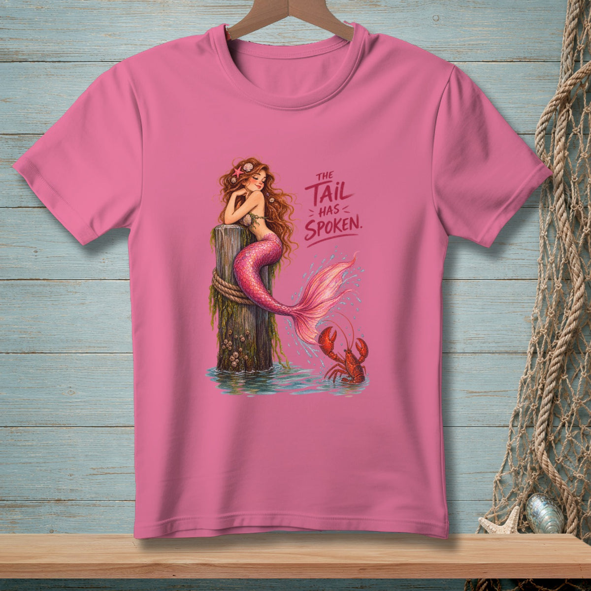 Pink t-shirt with a mermaid sitting on a post and the text "The tail has spoken."