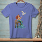 Mermaid with red hair sips a drink on a dock while a seagull flies by.