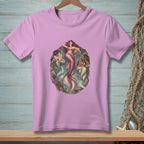 Three mermaids resting in a circular sea-themed graphic on a pink t-shirt.