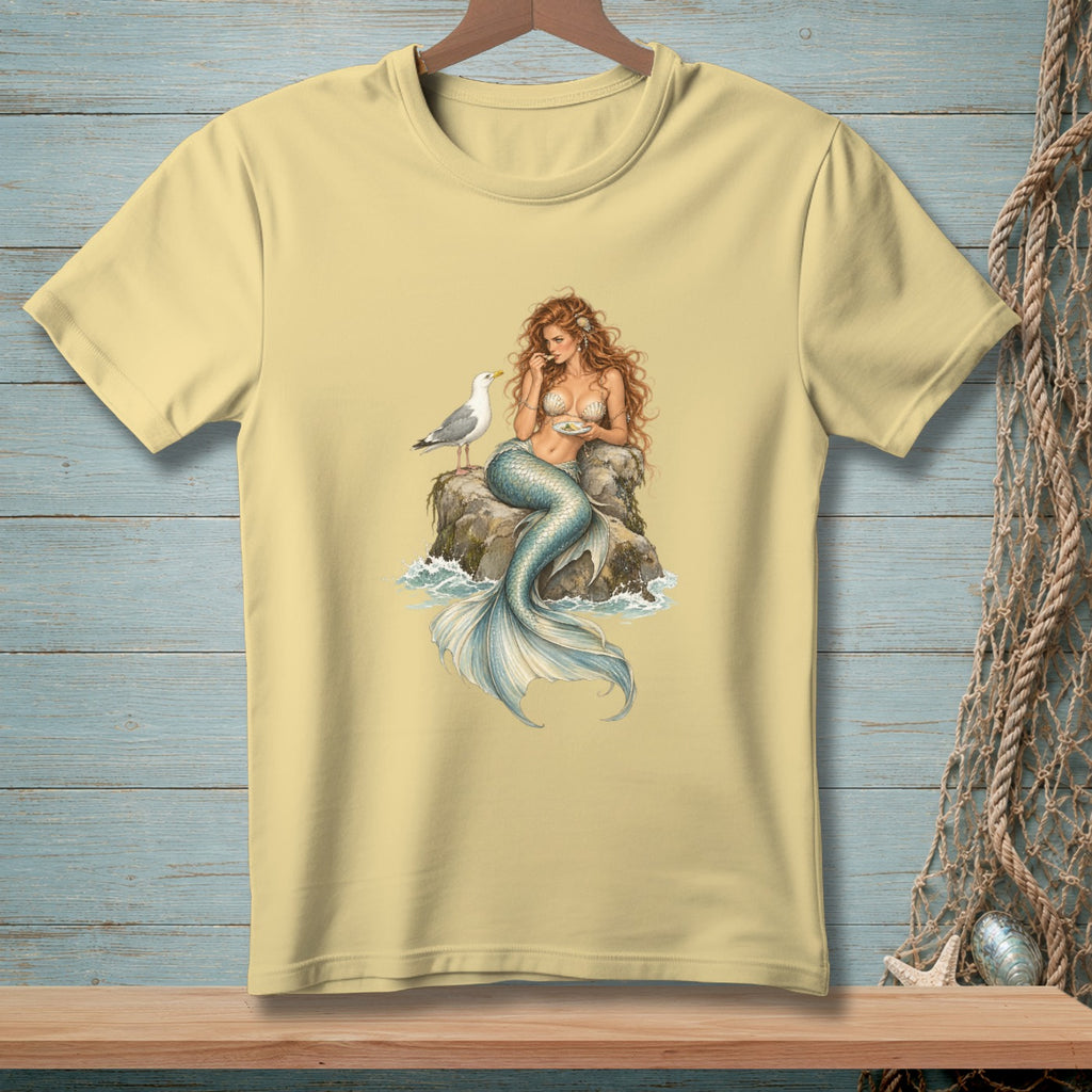 Mermaid sitting on rock with seashell bra and seagull eating food.