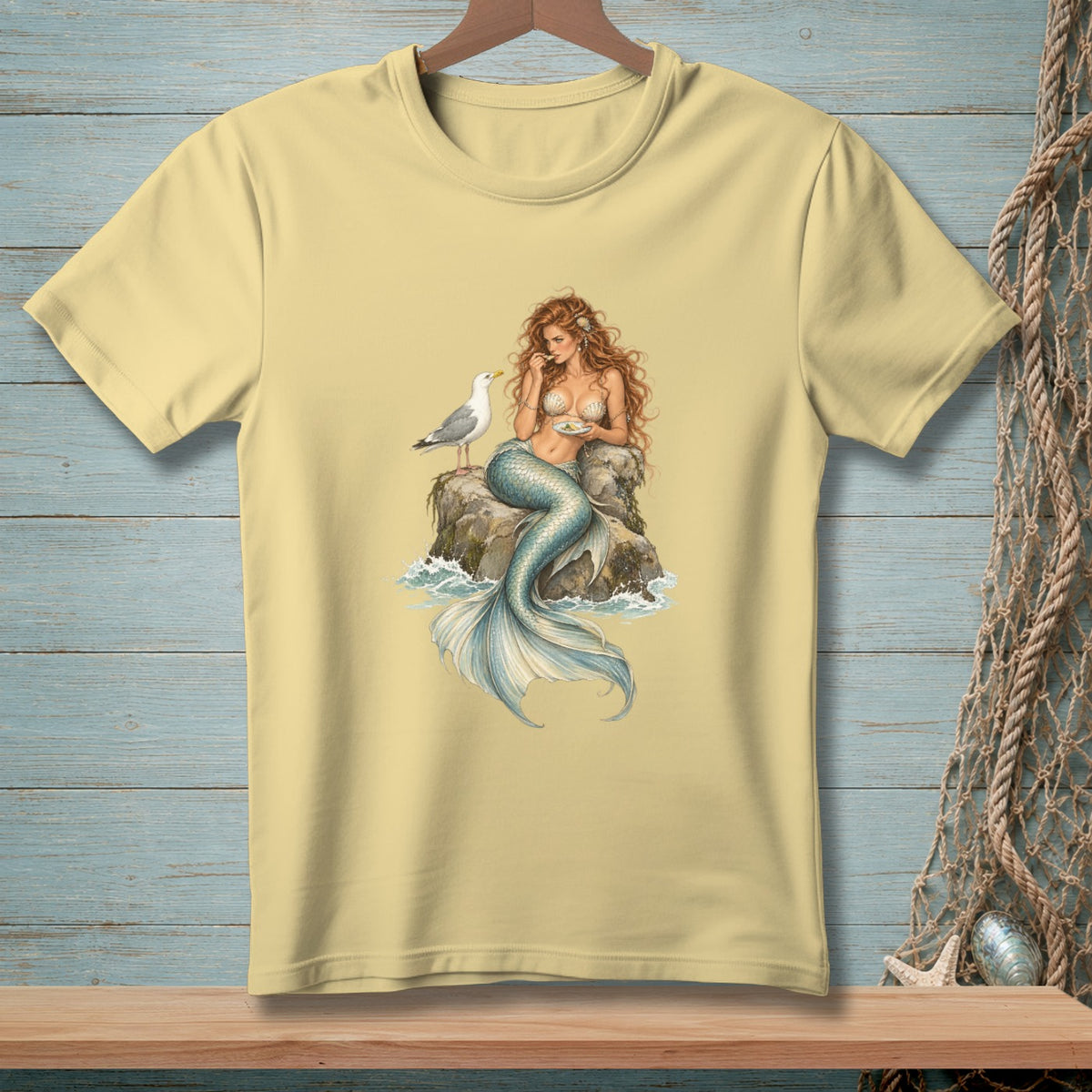 Mermaid sitting on rock with seashell bra and seagull eating food.