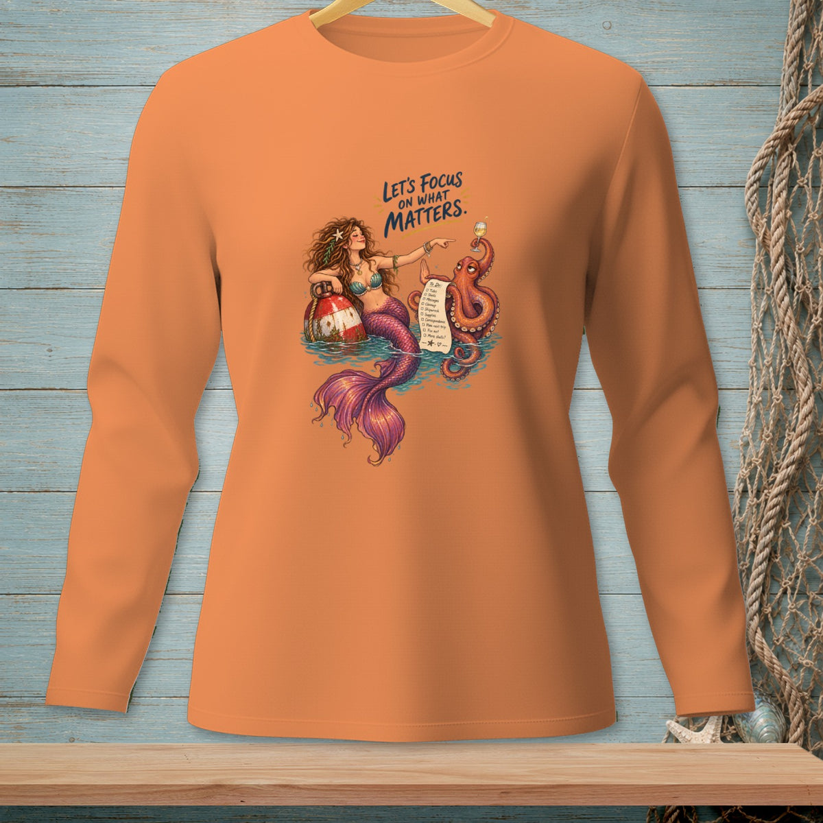 Orange long-sleeve shirt with mermaid, octopus, and "Let's Focus on What Matters" text.