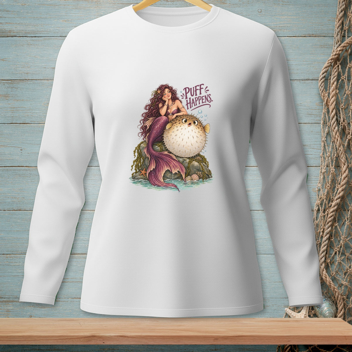 Mermaid and pufferfish illustration with "Puff Happens" text on a white long-sleeve shirt.