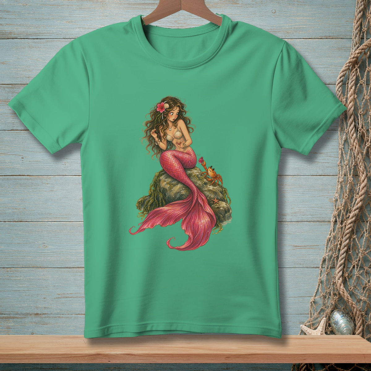Green t-shirt with a detailed illustration of a mermaid and a crab on a rock.