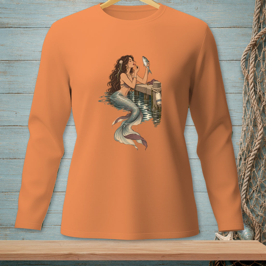 Mermaid with fish and makeup applying to her face on an orange long-sleeved shirt.