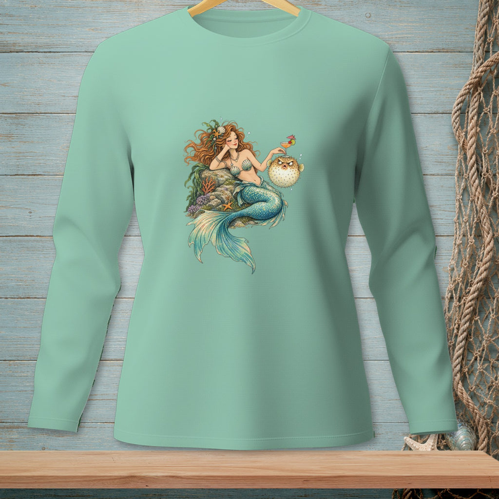 Mermaid with red hair and blue tail reclines with a pufferfish holding a cocktail.