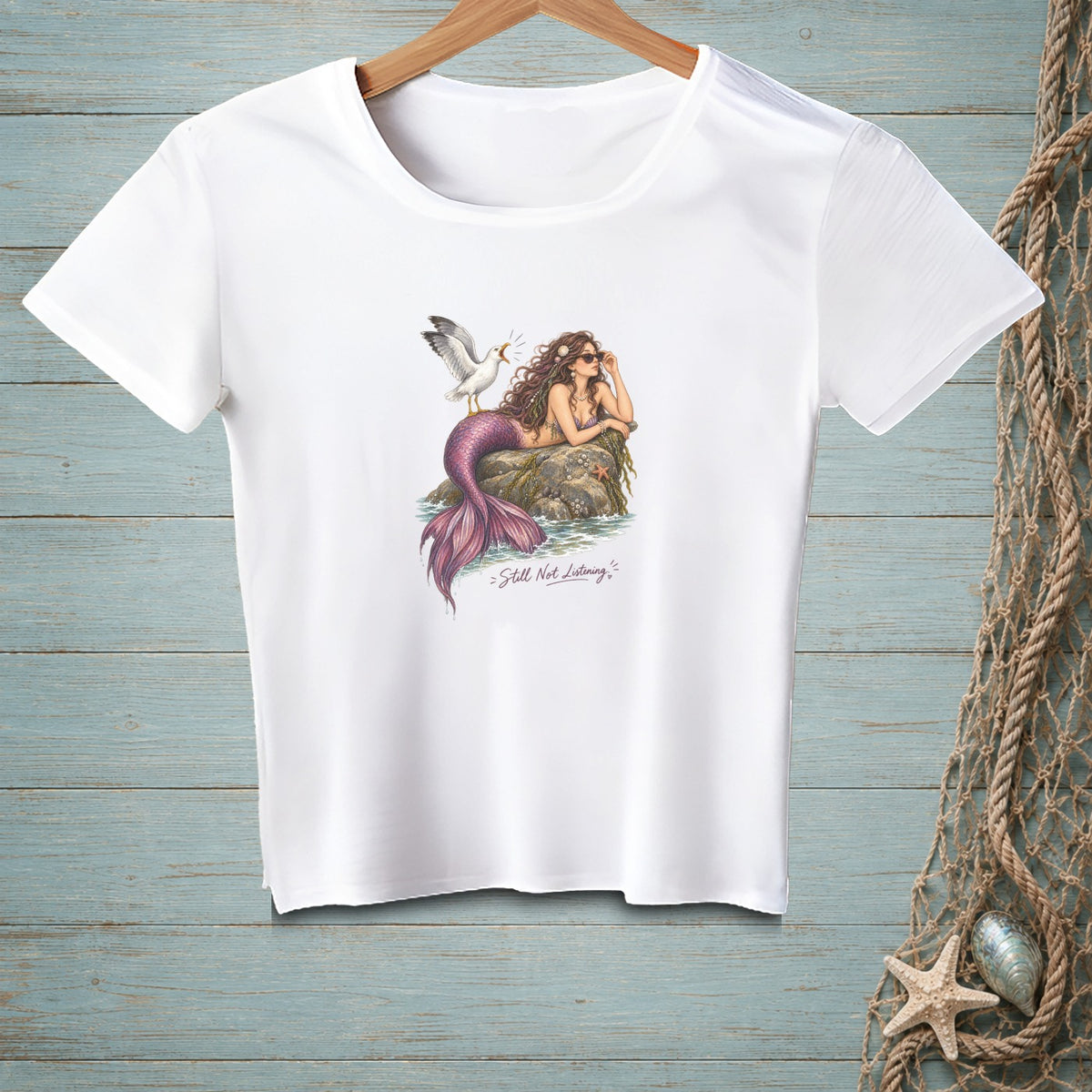 White t-shirt with illustration of a mermaid and seagull, and text "Still Not Listening."